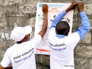 Des mobilisateurs sociaux mettent en place des affiches sur les mesures-clés pour éviter le choléra dans la zone de santé de Pakadjuma touchée par cette épidémie de choléra. Photo OMS/Eugene Kabambi