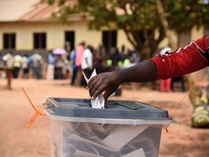 A man casts his ballot as people who were unable to vote on the first day of voting queue outside polling stations in Wakiso District, Uganda, on February 19, 2016. Electoral Commission (EC) expects a funding of $406.26 million to cover all its expenses r